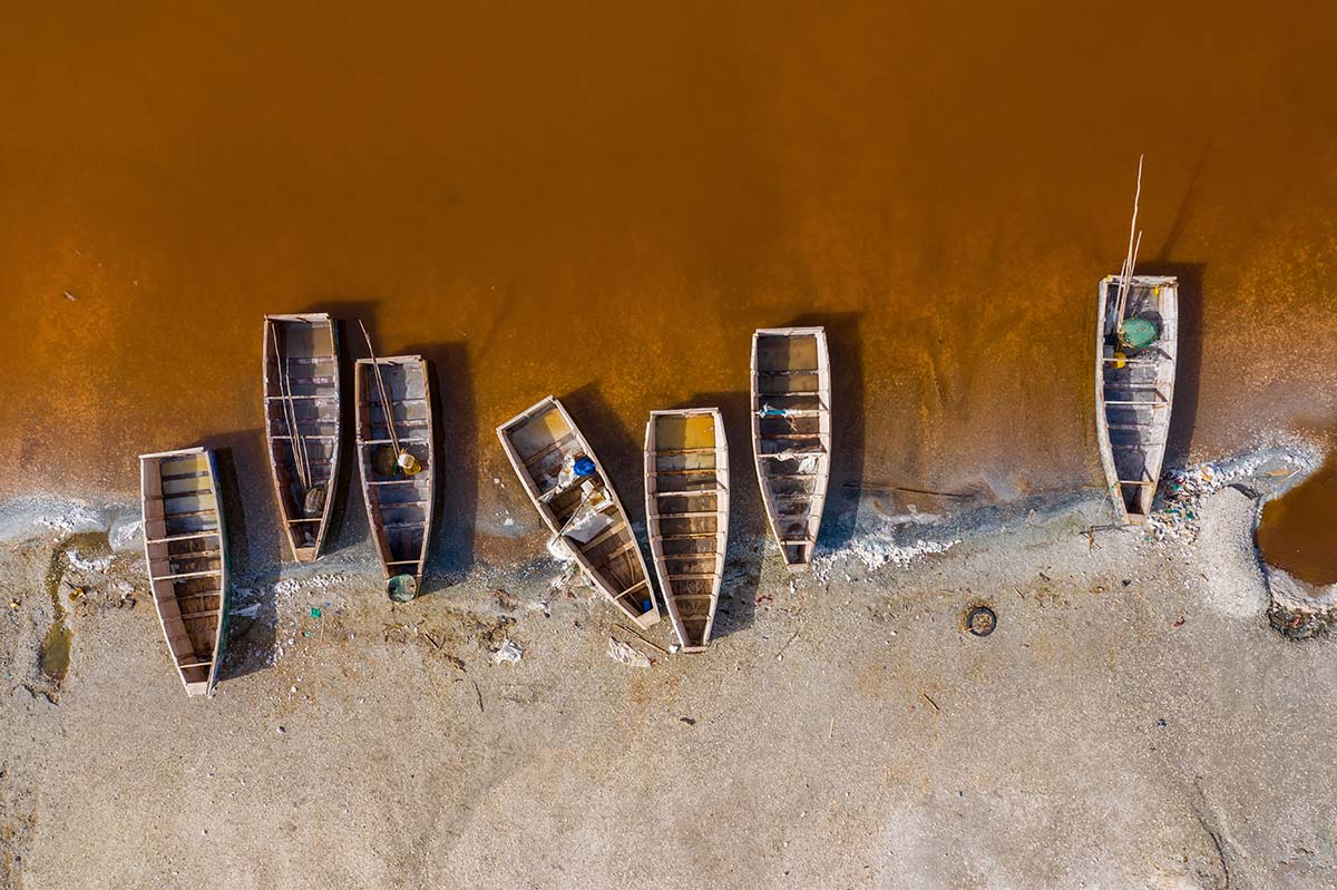 Aerial view of the small boats for salt collecting at pink Lake Retba or Lac Rose in Senegal. Photo made by drone from above. Africa Natural Landscape